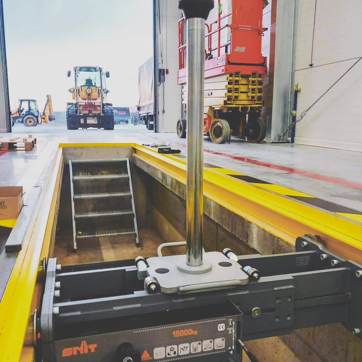 Podnośnik kanałowy SNIT SG15 o udźwigu 15 ton zamontowany w kanale nowoczesnego warsztatu samochodów ciężarowych i maszyn budowlanych